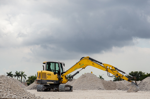 Yellow excavator with extended bucket at a landfill in South Florida USA.