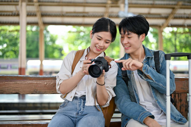 istock Cute Asian couple is talking while waiting for their train at the railway station. 1497075981