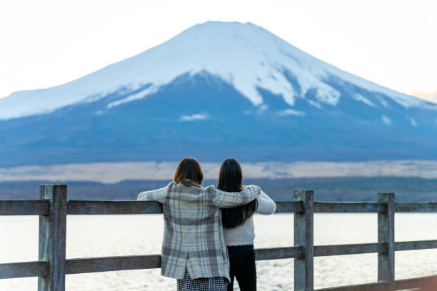 Asian woman friends travel lake Kawaguchi with mt Fuji covered in snow background. Happy Asian woman friends travel nature in Japan on autumn holiday vacation. Attractive girl traveler enjoy and fun outdoor lifestyle walking together at lake Kawaguchi with Mount Fuji covered in snow Lake Kawaguchi stock pictures, royalty-free photos & images