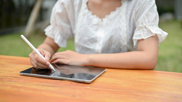 istock Close-up image of a female using her digital tablet at a table outdoors. 1497077828