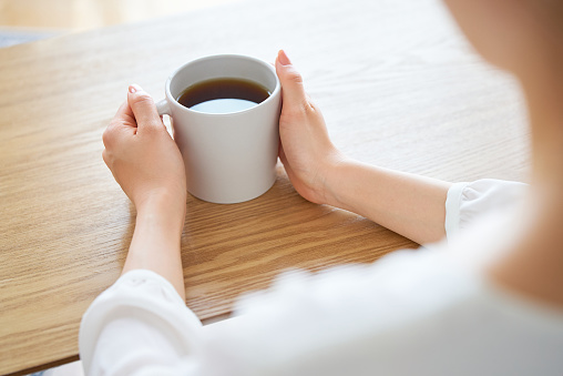 A woman's hand holding a mug and thinking in the room