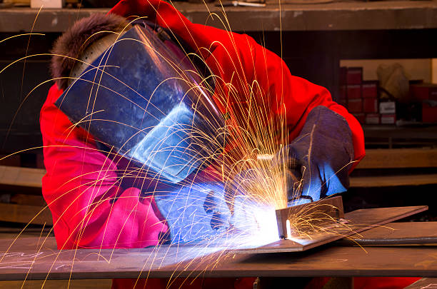 Welder in red overalls creates sparks