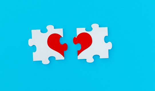 Two pieces of puzzle forming a red heart