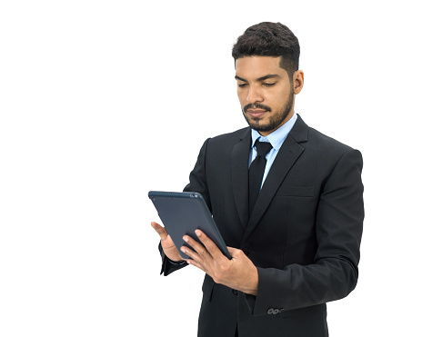 Young businessman with moustache and beard dressed in suit and necktie typing on tablet computer. Portrait on white background with studio lighting. Isolated