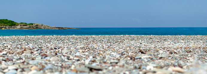 the sea shore with stones and the blue sky.
