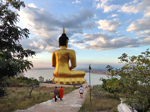 People walking at the Big Buddha overlooking Mekong river at Wat Phousalao (Golden Buddha temple), in Pakse, the capital and most populous city of province of Champasak, and the second most populous city in Laos.