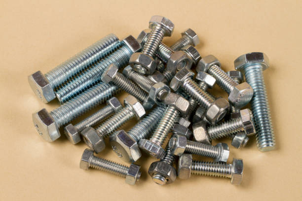 a bunch of new bolts and nuts on a yellow background. - bolt nut screw hardware store imagens e fotografias de stock