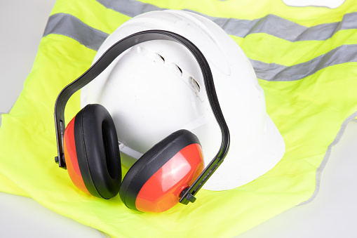 Standard flat lay safety worker protection equipment noise canceling headphones helmet and yellow reflective safety jacket vest
