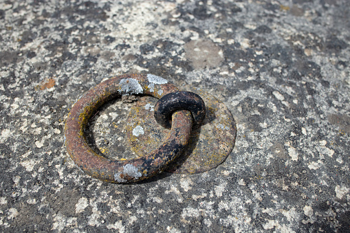 Heavy metal ring handle fixed in old and weathered concrete, soft focus close up