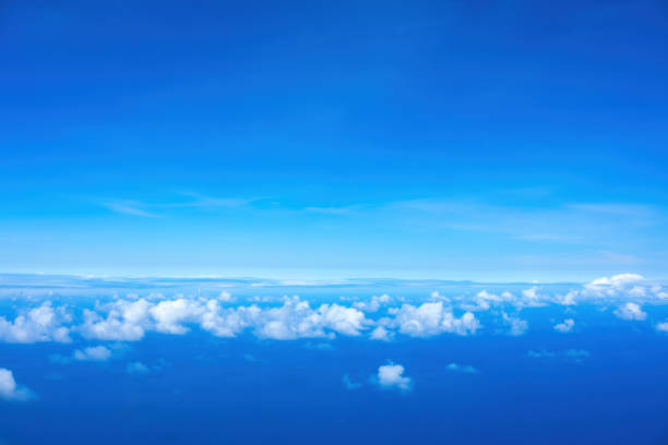 istock Line of fluffy white clouds just below horizon over blue ocean 1497100138
