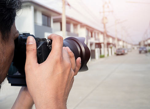 Close up hands of Young Asian photographer taking pictures of housing estates. Property and real estate concept.