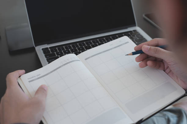 istock 2023 Calendar event planning timetable agenda plan on organize schedule. Event planner agenda organizing by organizer schedule. Business man hand note on notebook with calendar planner on office table 1497102677