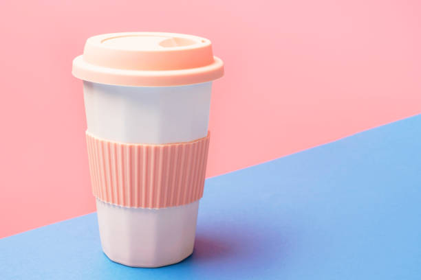 istock Reusable ceramic glass for coffee with silicone lid on pink and blue background. 1497103789