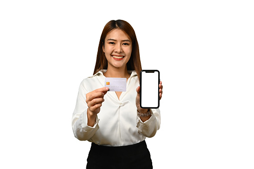 Beautiful woman holding credit card and showing smartphone with blank screen isolated on white background.