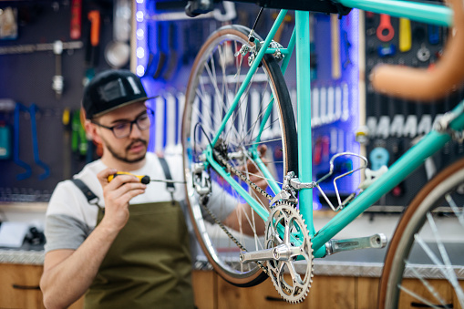 Cycle repair shop owner dedicated to his work to repair and renew a vintage bicycle to make it look new again.