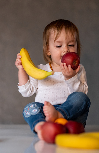 baby is playing with fruit and trying to eat apple