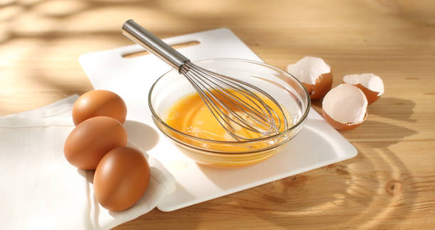 Whisking eggs. Whipped raw eggs in a bowl. Close -up.
