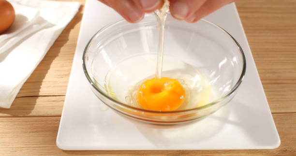 istock Hands breaking an egg. Raw egg pours into bowl. Close -up. 1497112275