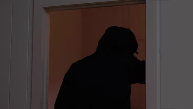 Silhouette of a man entering a room with a knife