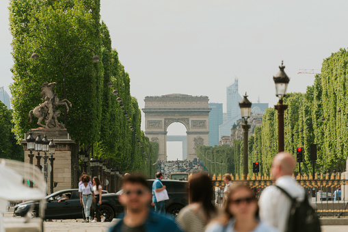 Paris, France - May 21, 2023: The Arc de Triomphe seen from Place de la Concorde and glimpse of La Défense. The Arc de Triomphe is one of the most famous monuments in Paris, France, standing at the western end of the Champs-Élysées at the centre of Place Charles de Gaulle. The location of the arc is shared between three arrondissements: 16th, 17th and 8th. The Arc de Triomphe honours those who fought and died for France in the French Revolutionary and Napoleonic Wars, with the names of all French victories and generals inscribed on its inner and outer surfaces.