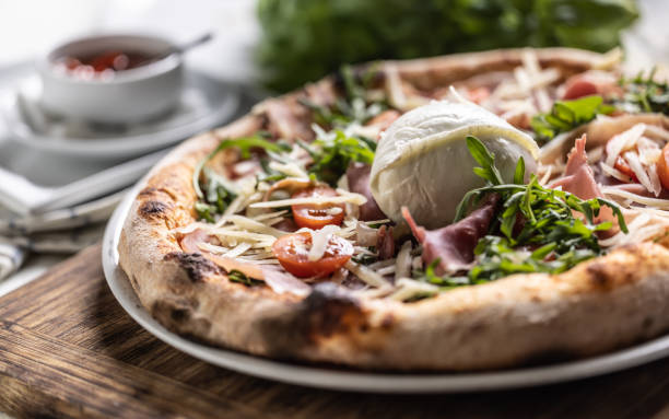 istock Ham, ruccola, tomatoes and cheese pizza with entire mozzarella di bufala Campana on top. 1497120469