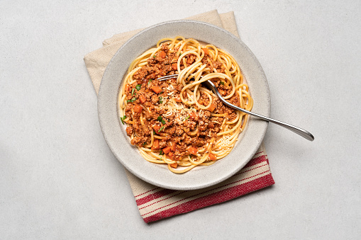 Spaghetti bolognese pasta in ceramic plate on light gray background