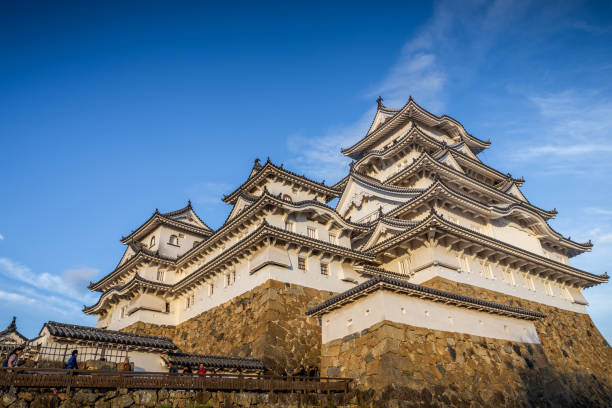 Osaka, Japan - November 23, 2018: Ancient japanese central building called Osaka castle painted by white color built on top of palace area with cloudy blue sky in autumn.