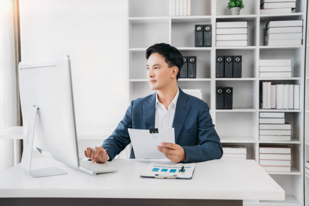 istock Asian businessman working at office with laptop and documents on table. 1497128484