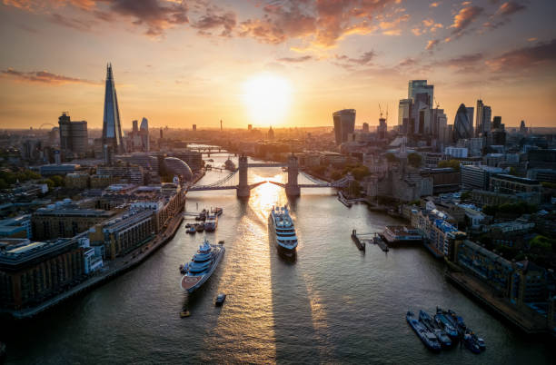 Panoramic aerial sunset view of the skyline of London Panoramic aerial view of the skyline of London, England, with a ship crossing under the Tower Bridge during a beautiful sunset thames river stock pictures, royalty-free photos & images