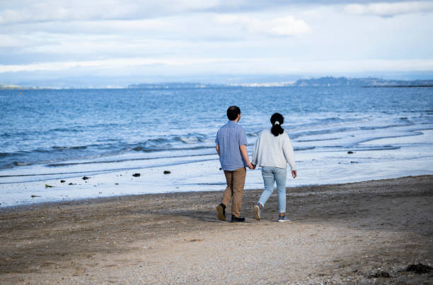 istock Couple holding hands and walking on beach.  Auckland. 1497132555