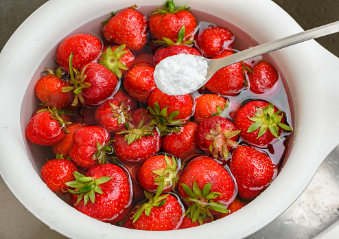 Rinsing fresh strawberry fruit in water with the addition of baking soda close-up top view