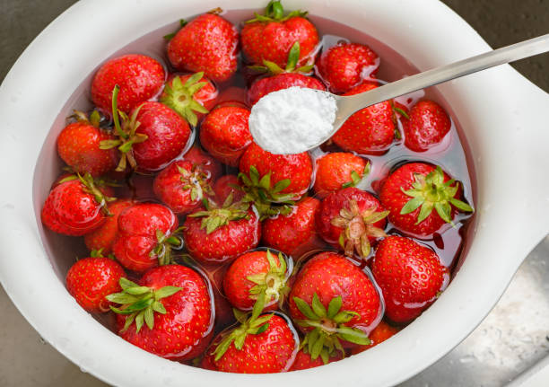 płukanie świeżych owoców truskawek w wodzie z dodatkiem sody oczyszczonej - washing fruit preparing food strawberry zdjęcia i obrazy z banku zdjęć