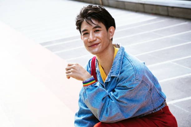 Portrait of a asian gay man Portrait of a asian gay man holding a backpack while waiting the LGBTQI parade queer man facing camera stock pictures, royalty-free photos & images