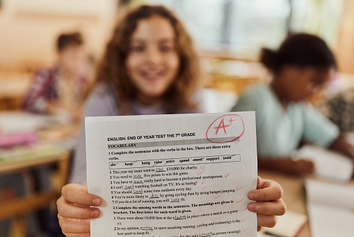 Close up of a schoolgirl showing her A grade on a test at elementary school.