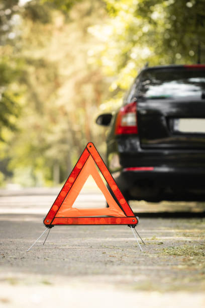 istock Red triangle, red emergency stop sign and black car with technical problems in the blurred background. Emergency stop of the car on the road. Safety procedure while having a vehicle broken down 1497138095