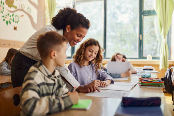 istock Happy black teacher and school kids learning at elementary school. 1497138806