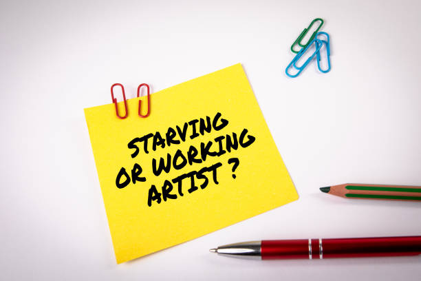 istock Starving or working artist. Yellow sticky note with text on a white background 1497140582