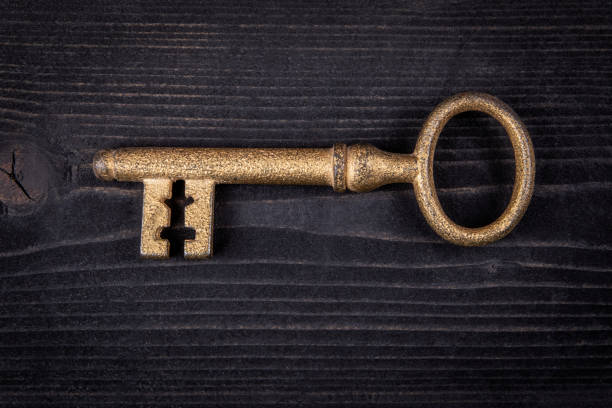 istock Gilded antique key on dark wood texture background. Close up 1497140603