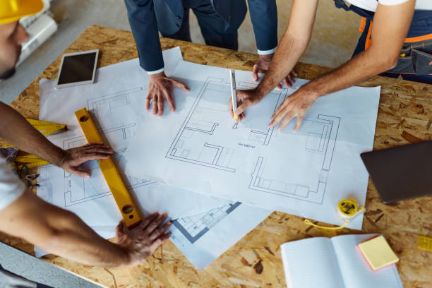 istock Above view of architect and manual workers examining blueprints at construction site. 1497142747