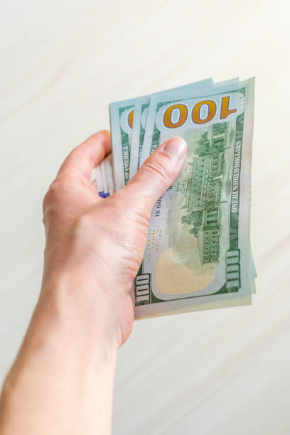 istock A stack of one hundred dollar bills is held by a woman's hand. 1497144323
