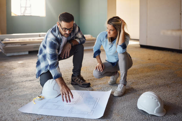 istock Young couple examining housing plan at construction site. 1497144372