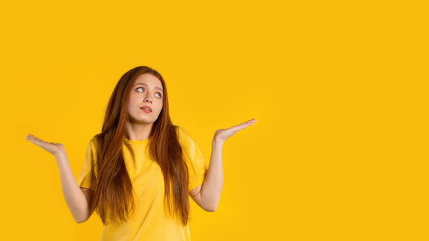 istock Confused pretty woman, shoulders up - can't help, makes gesture of I dont know. Difficult question, guilty reaction, puzzled stylish woman on yellow background. 1497144770