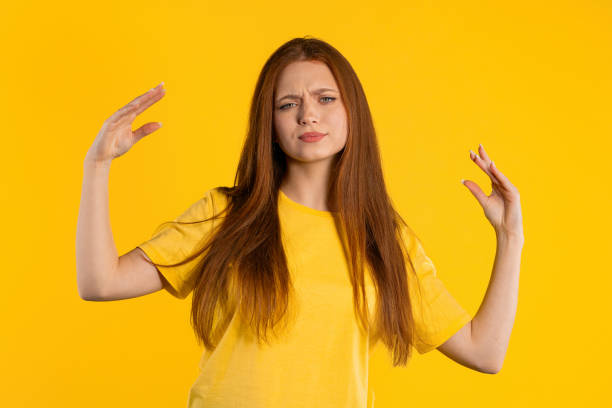 istock Irritated ginger woman showing bla-bla-bla gesture with hands, rolling eyes on yellow background. Empty promises, blah concept. Lier. 1497144789
