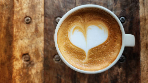 caffè latte art a forma di cuore in una tazza da caffè in ceramica posta su un tavolo di legno con spazio per copiare - morning cream food milk foto e immagini stock