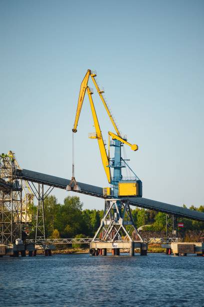 istock Large yellow crane standing on a dock by a river, with a bridge in the background 1497146579