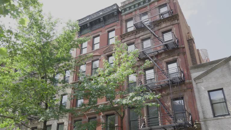 Brick four and five story walk up apartment buildings in New York city in rows with fire escapes and ornate finishings