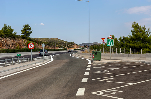 View of the Athens-Thessaloniki national highway, road signs and part of the parking on a sunny summer day (Greece)