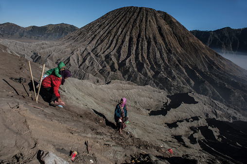 PROBOLINGGO, EAST JAVA, INDONESIA - August 11, 2014 : Tenggerese gather at crater of Mount Bromo during the Yadnya Kasada Festival on August 11, 2014 in Probolinggo, East Java, Indonesia. The Tenggerese people are a Javanese ethnic group in Eastern Java who claim to be the descendants of the Majapahit princes. The origin of the festival lies in the 15th century princess named Roro, the principality of Tengger with her husband Joko Seger, and the childless couple asked the mountain Gods to help in bearing children. The legend says the Gods granted them 24 children but on the provision that the 25th must be added to the volcano in sacrifice. The 25th child, Kesuma, was finally sacrificed in this initial after refusal, and the tradition of throwing sacrifices into the Caldera to appease the mountain Gods continues today.