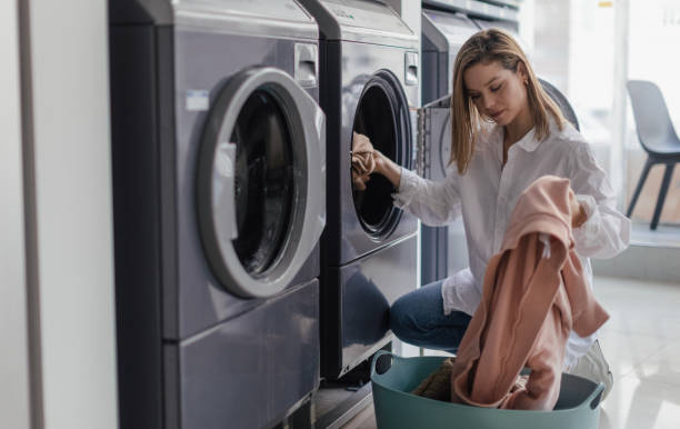 istock Young woman loading washing machine in public laundry. 1497148750