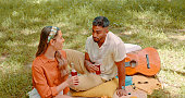 Couple, nature picnic and drinking juice in forest for a summer getaway with conversation for bonding. Talking, drink and man and woman in forest for a valentines day date with love and care